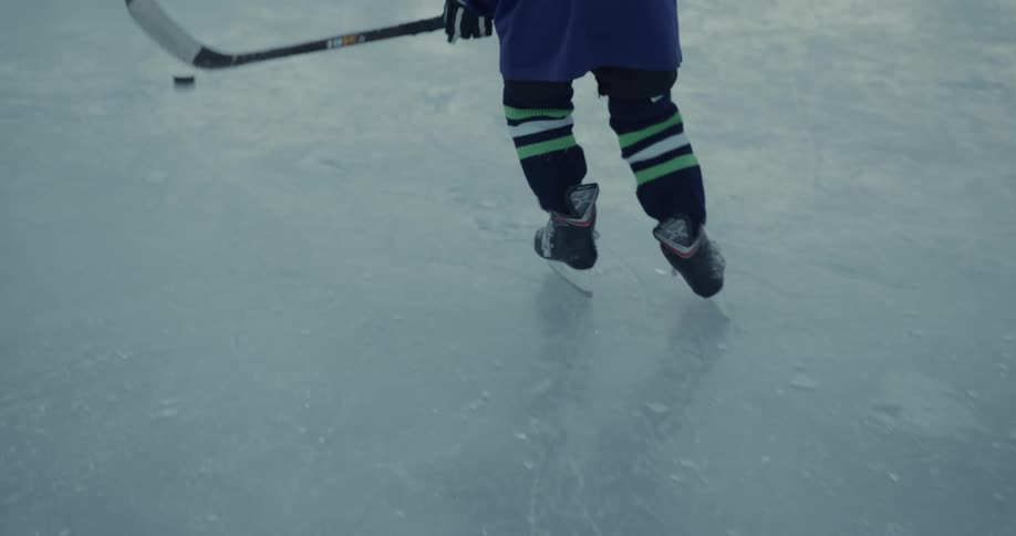 Young hockey player practices on outdoor ice rink as another child practices in the background