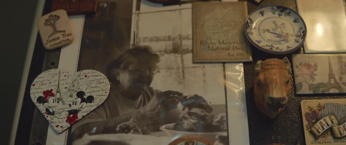 Magnets hold picture of older woman cooking in kitchen on the refrigerator door