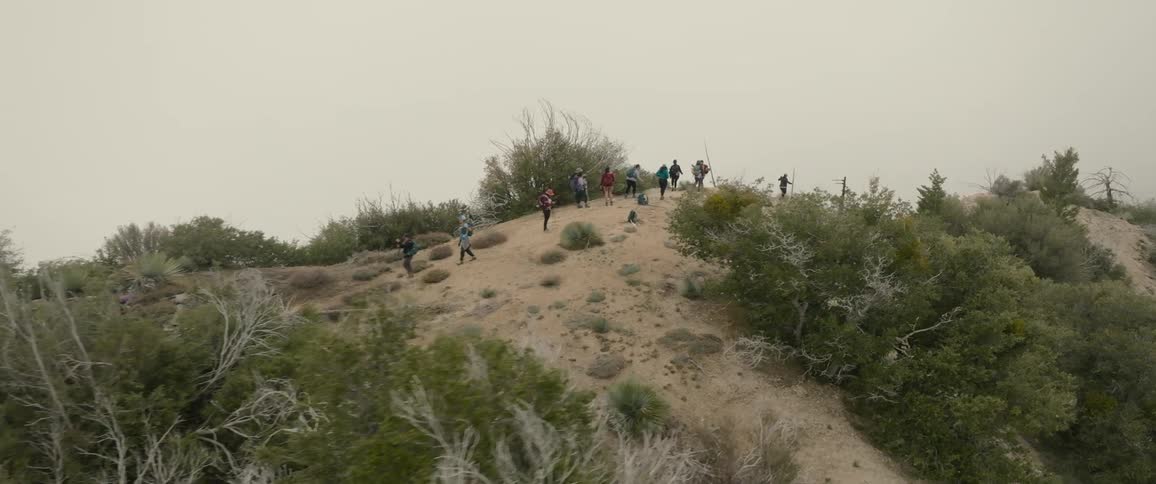 A group of female hikers walk across the ridge of a tall hill
