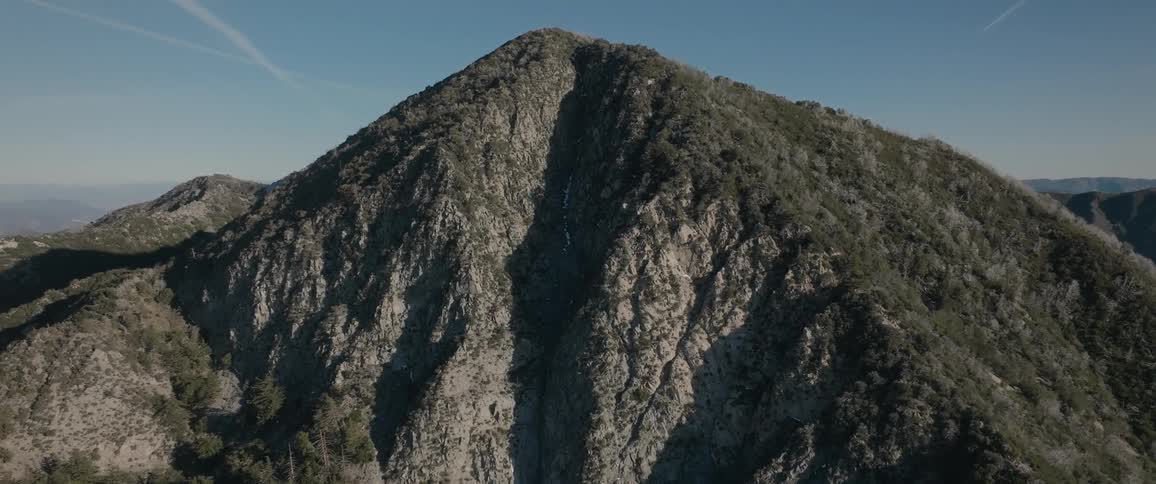 Aerial of a large mountain on a mostly sunny day