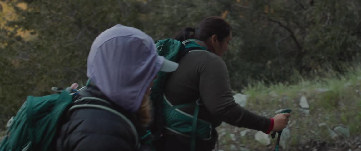 Small group of people wearing backpacks hike up rocky mountain terrain