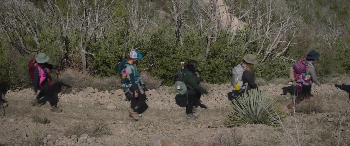 Small group of people hike rocky terrain during the day