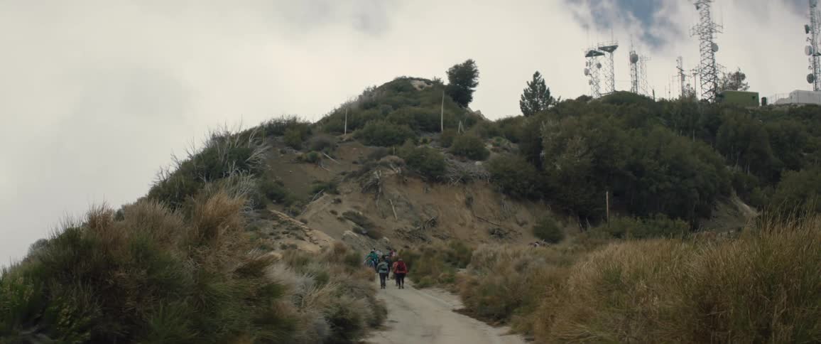 A group of women hike uphill together under a very cloudy sky