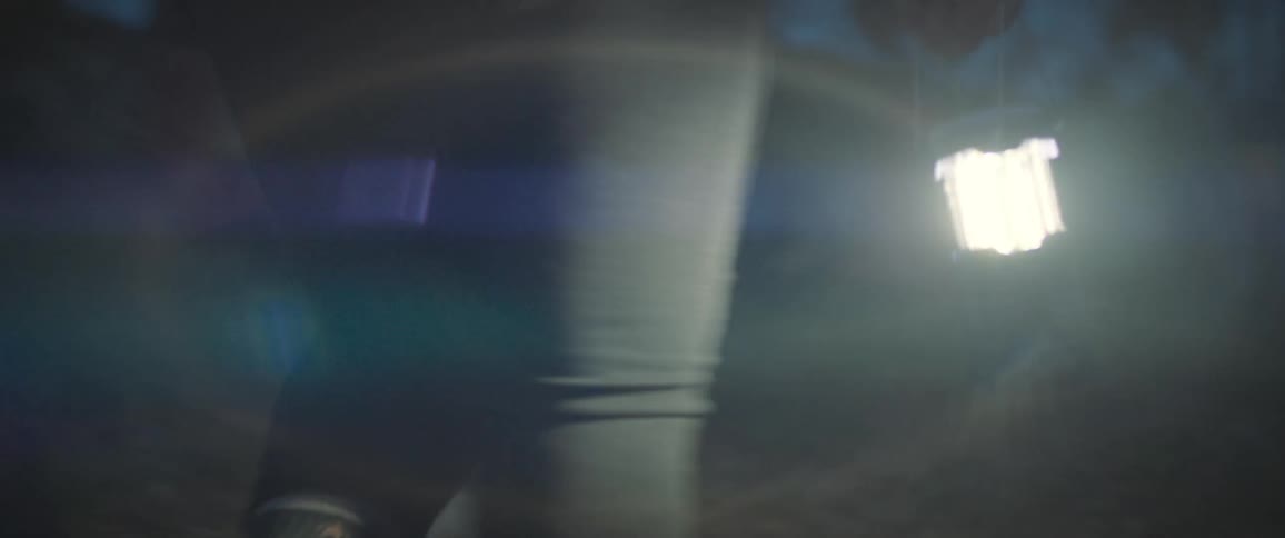 Closeup of a woman walking with a handheld flashlight in the middle of a forest at night
