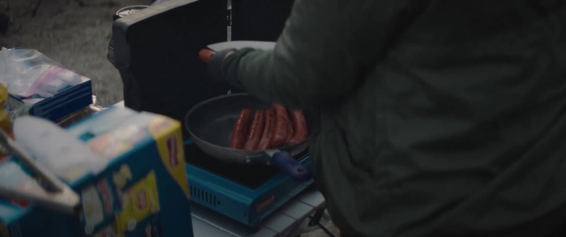 A clip of a person cooking sausage