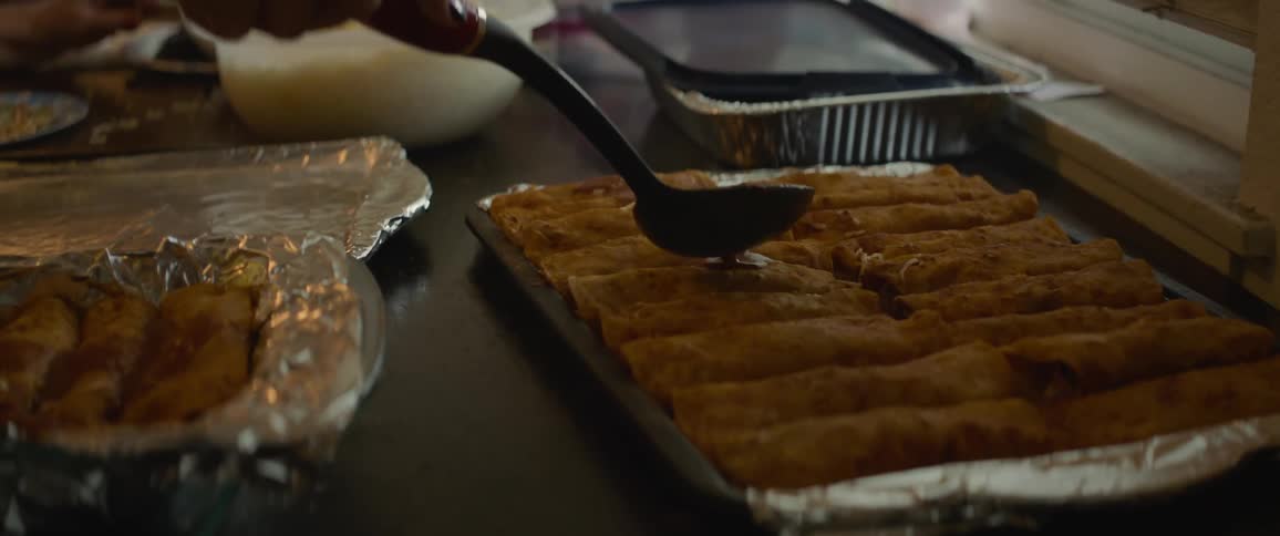 A person pours sauce on a tray of food