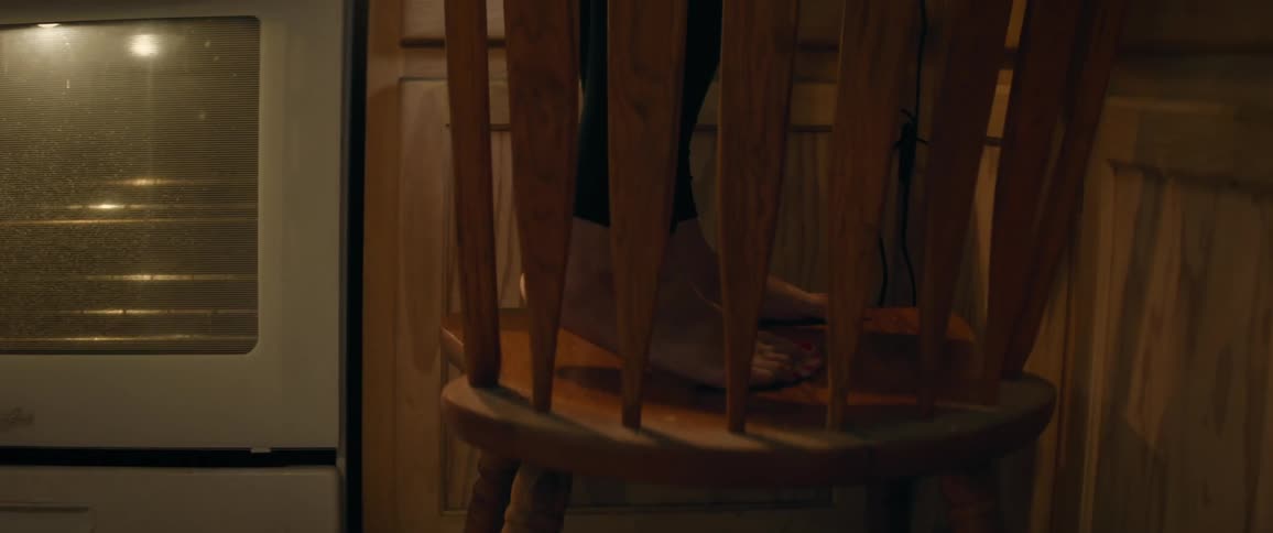 Feet stand on wooden chair in kitchen near oven