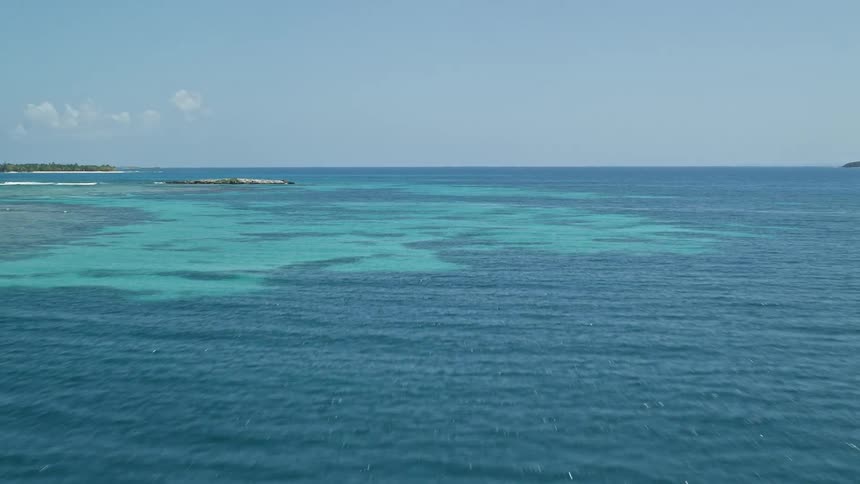 An ocean with very blue water and on the left side a small island