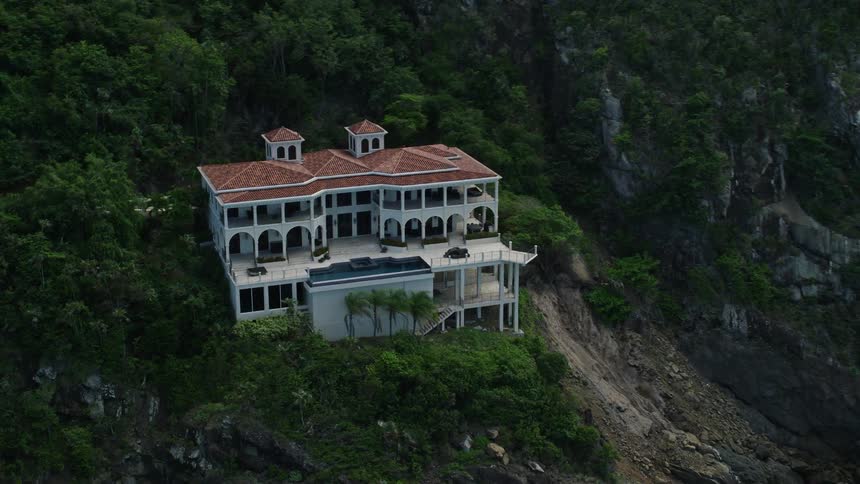 Villa surrounded by forest perches on seaside slope over cave