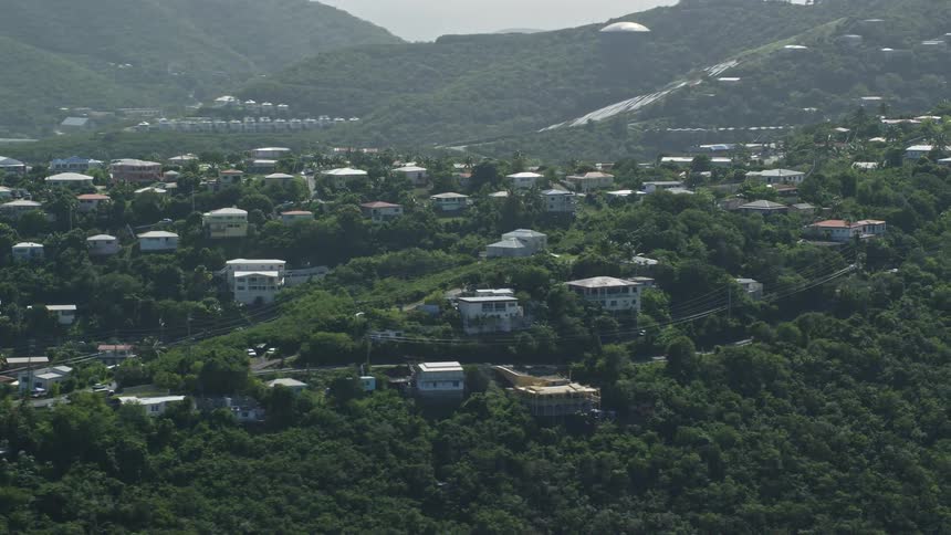 Aerial view of mountain range area with houses and buildings on the higher parts surrounded by vegetation during day time