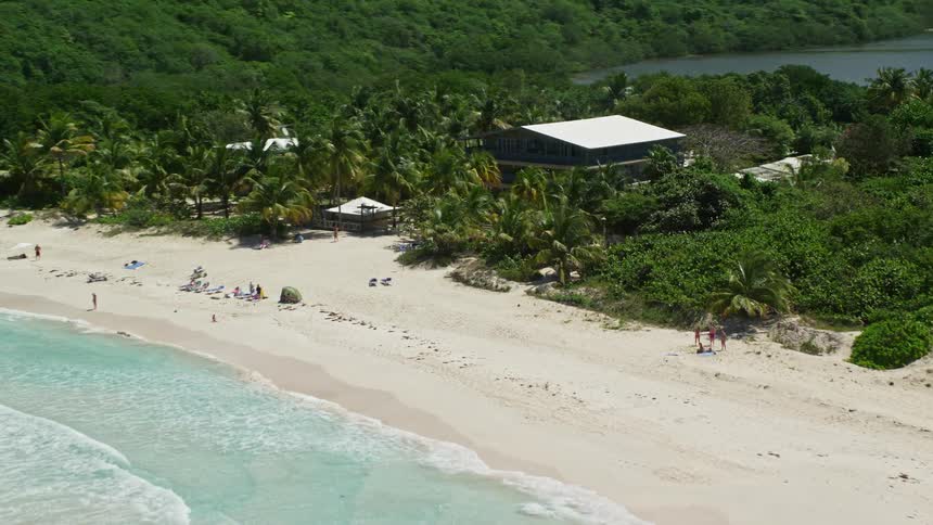 Aerial view of a beach with turquoise blue water and a tropical forest