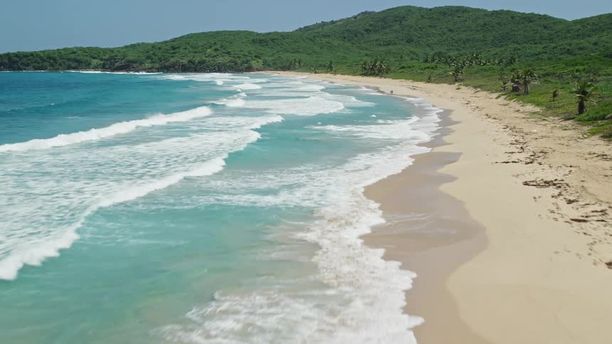 Waves crash against the shore of the island
