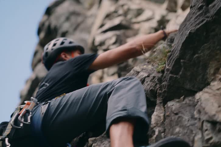 A man climbing a rocky mountain wearing safety equipment