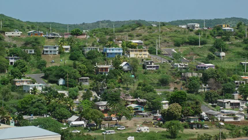 A small town with several houses and some of them on top of a hill and there are many trees spread throughout the town