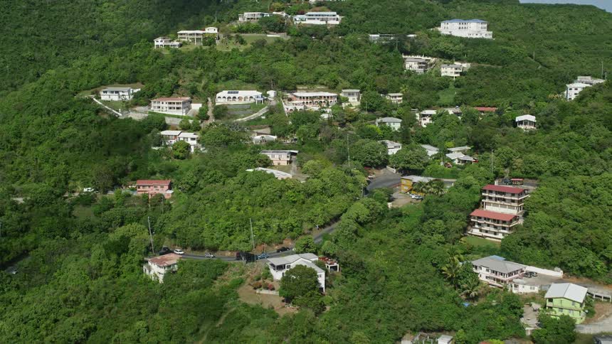 Aerial panorama of residential houses and resorts amidst mountains with vegetation