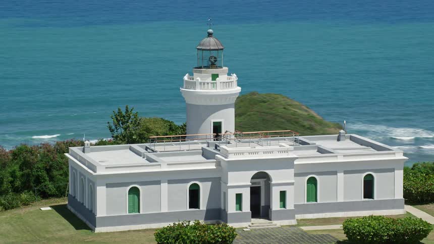 An aerial view of a lighthouse out on a hill