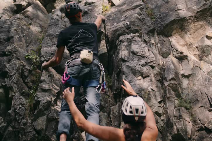 Two rock climbers climb rugged cliff face