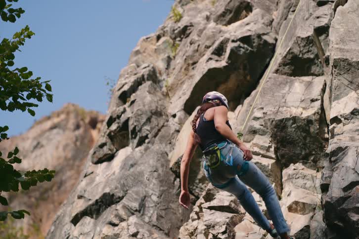 Woman descending a rocky wall of a mountain with safety equipment