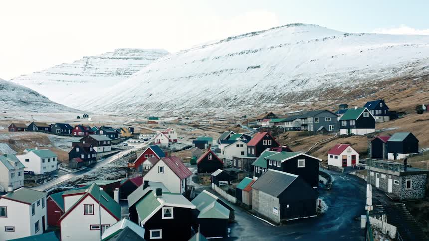 Aerial view of a small town in greenland next to snow covered mountains