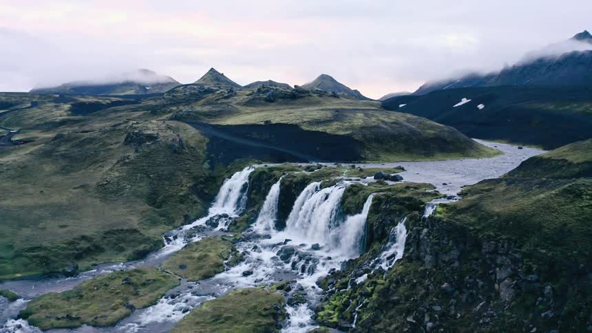Panorama of a river in free fall over a waterfall surrounded by mountains on a cloudy day