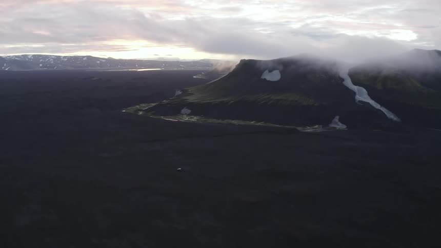 A car passing through a volcanic valley during dawn
