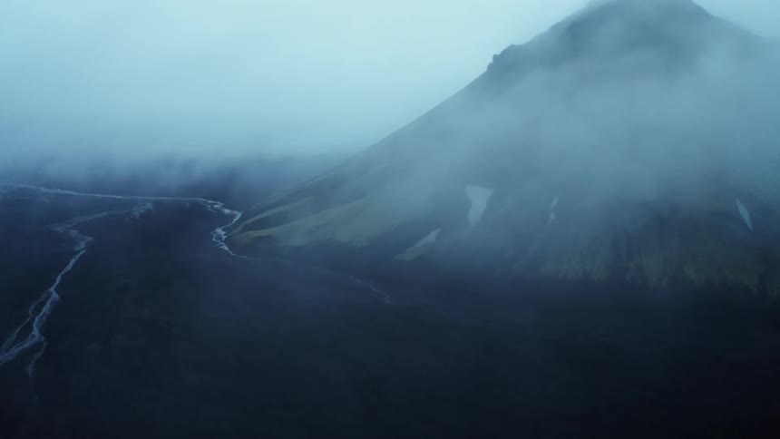 View of a mountain with moss on black soil on a cloudy day
