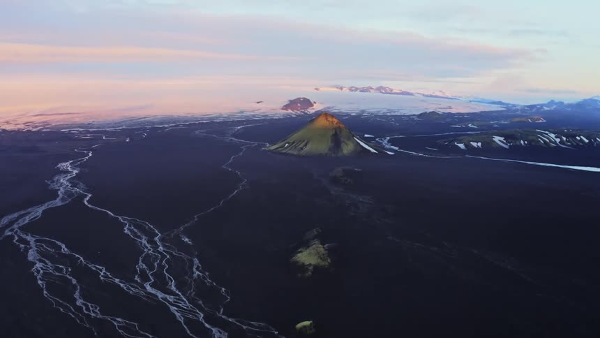 A volcano sits dormant within dark colored land