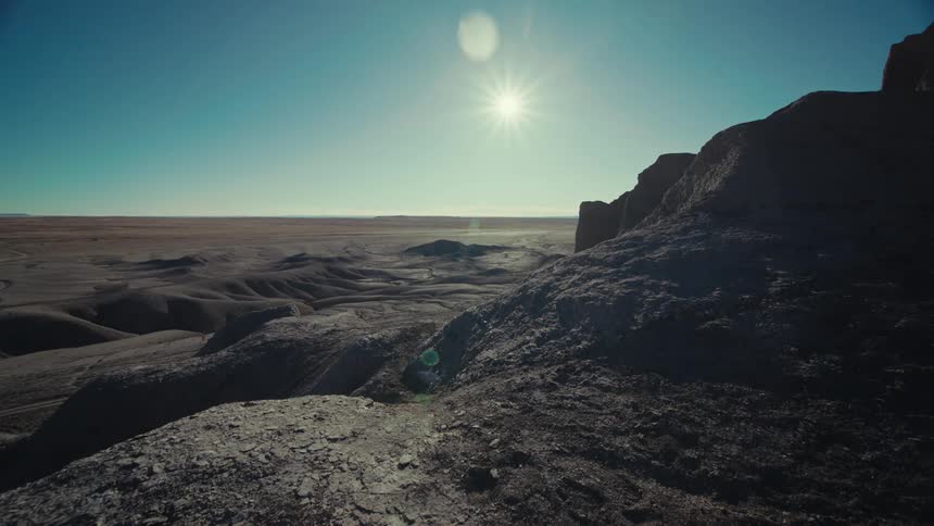 A region with small rock formations and the sun shining in a blue sky