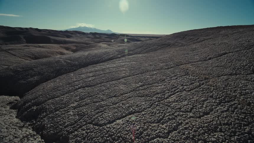 Rough arid hills stretch to mountain on horizon on sunny day