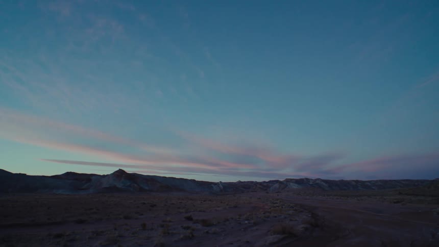 Mountain range borders plain under red tinted clouds