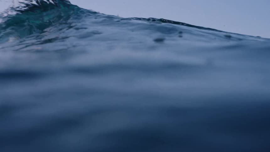 Crystalclear wave breaking in the sea on a morning with a purple dawn sky