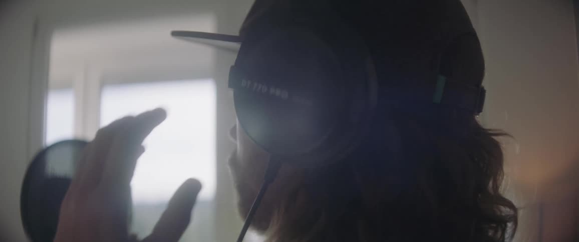 A man stands in front of a microphone and puts a headphone on his head