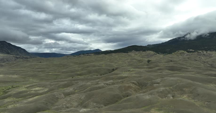 View of muddy ground with a mountain range around on a cloudy day