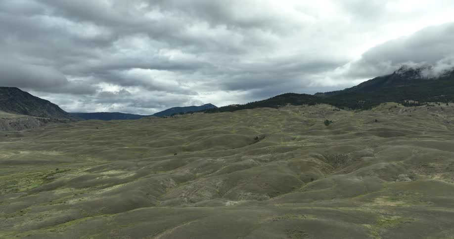 Panoramic view of a desert land with mountain range around on a cloudy day