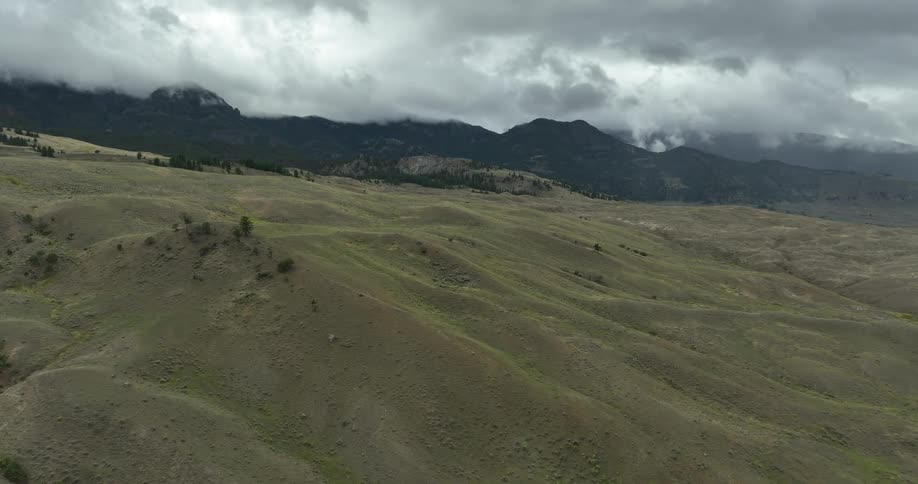 An aerial view of some mountains with clouds in the distance