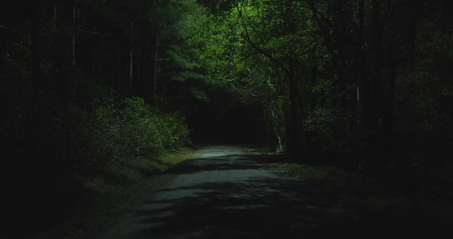 Bright white light hovering over a road in a rural area at night search helicopter light
