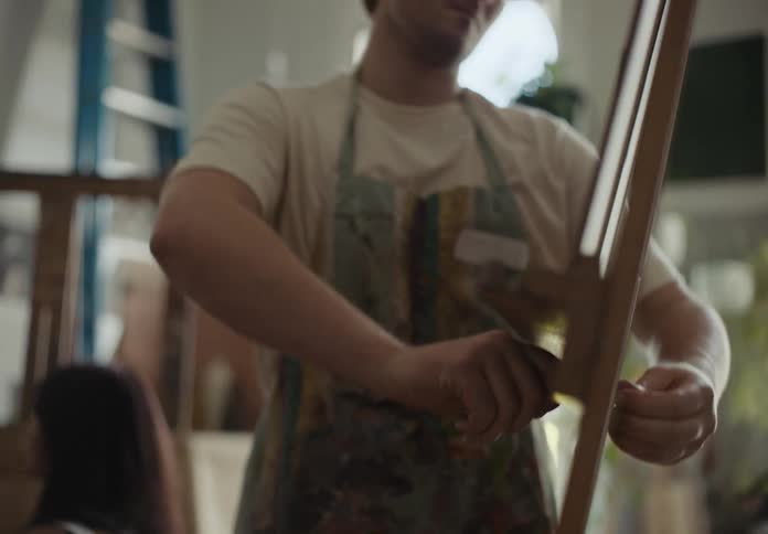 A painter sets up a canvas on a tripod stand