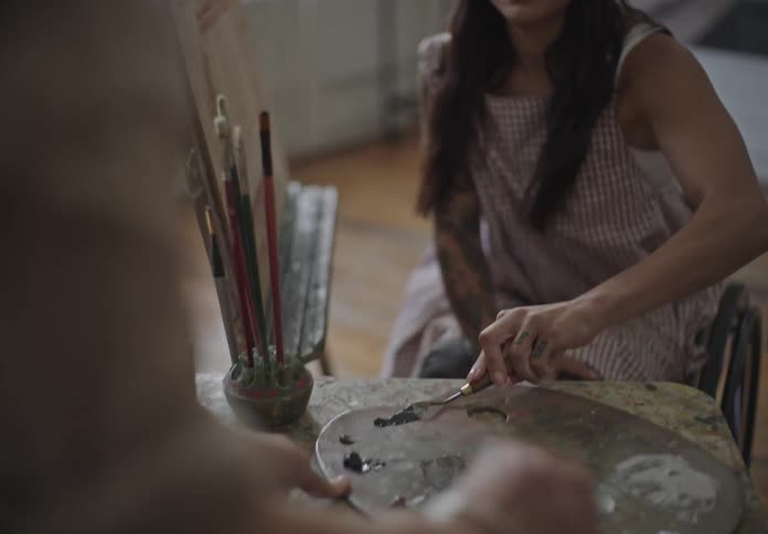 A woman mixing paint colors on a palette