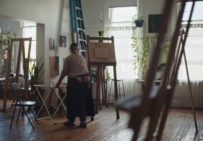 A woman arranging furniture in an art room