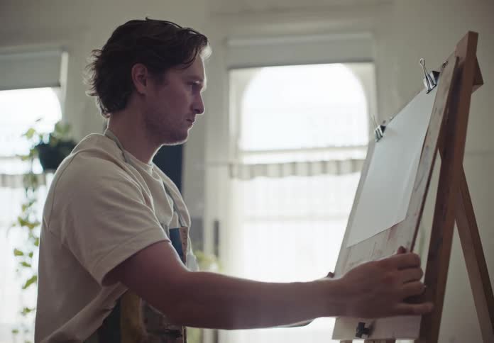 Artist prepares easel near window indoors