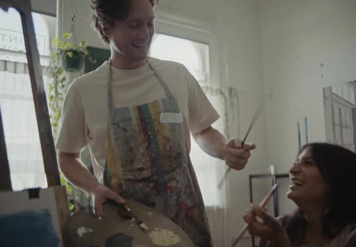 A pair of artists play with each other in a painting studio