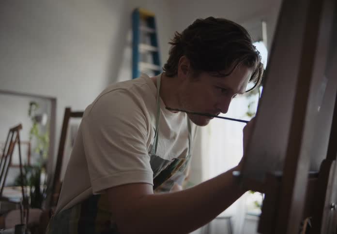 A man painting a picture concentrated on a house