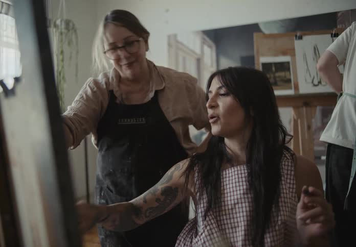 Three people in a room painting on canvas and chatting