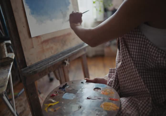 Woman painting a picture with another woman beside her observing