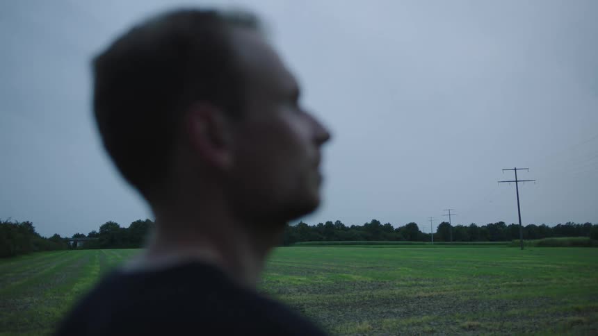 A man contemplating beside the plain grass field