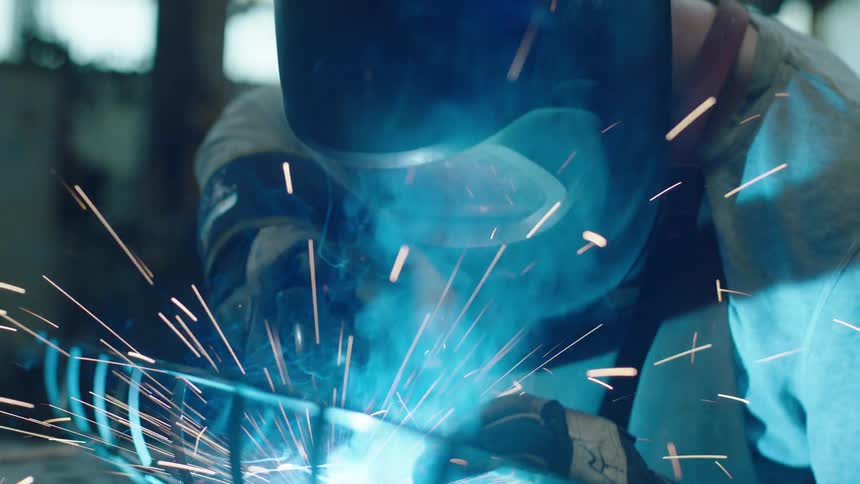 A person using a power tool on an iron grill