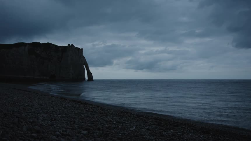 A rocky beach with cliffs under a cloudy sky
