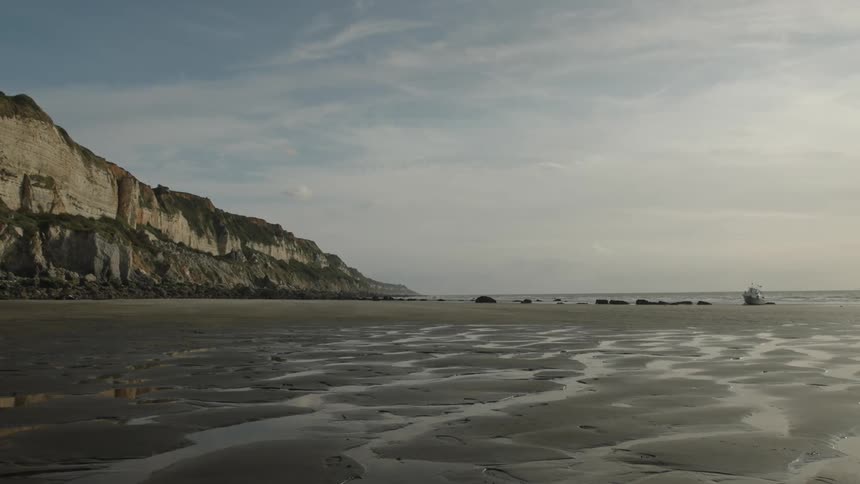Wide view of the wet sand with the sea to the side and the back on a morning sky with clouds