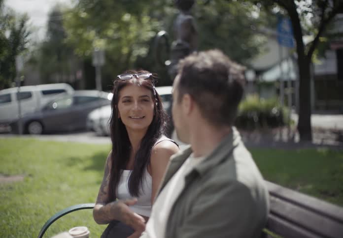 A couple of friends sitting on a bench in the park talking