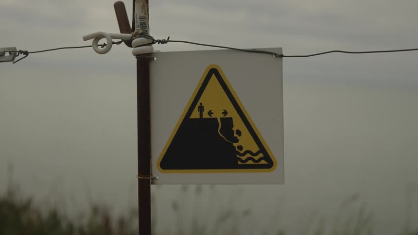 A sign warning of danger on a fragile cliff